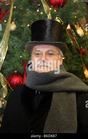 Un periodo vittoriano vestito uomo di fronte a un albero di Natale Foto Stock