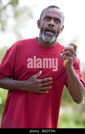 Attacco d'asma. Uomo anziano tenendo il suo petto come egli si trova in difficoltà a respirare durante un attacco d' asma. Foto Stock