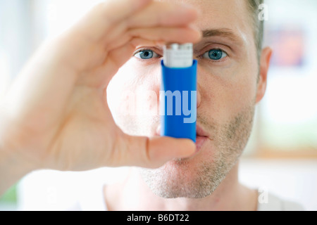 Uomo che utilizza un inalatore per trattare un attacco d' asma Foto Stock