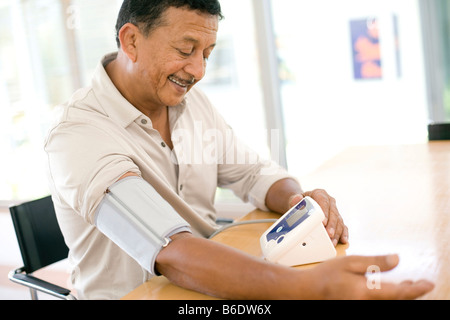 La misurazione della pressione sanguigna. L'uomo controllare la sua pressione del sangue a casa con uno sfigmomanometro elettronico. Foto Stock