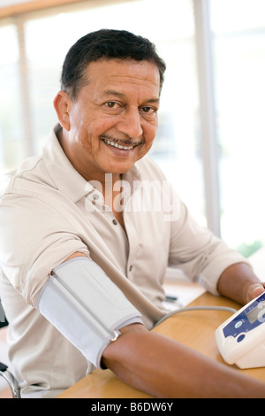 La misurazione della pressione sanguigna. L'uomo controllare la sua pressione del sangue a casa con uno sfigmomanometro elettronico. Foto Stock