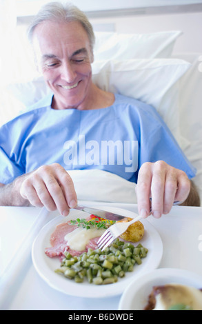 Paziente senior di mangiare un pasto dell'ospedale. Foto Stock