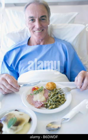 Paziente senior di mangiare un pasto dell'ospedale. Foto Stock