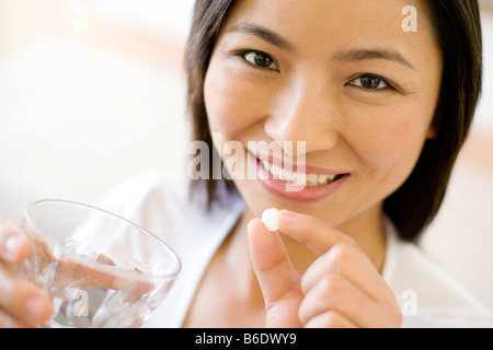 Donna di prendere una pillola con un bicchiere d'acqua. Foto Stock