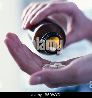 Antidolorifici. Mano versando il killer del dolore (oranalgesic) pillole da una bottiglia. Foto Stock