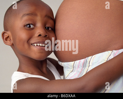 La donna incinta e il figlio. 4-anno-vecchio ragazzo abbracciando il ventre gonfio di sua madre. Foto Stock