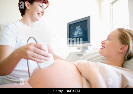 Donna incinta facendo a ultrasuoni clinica Foto Stock