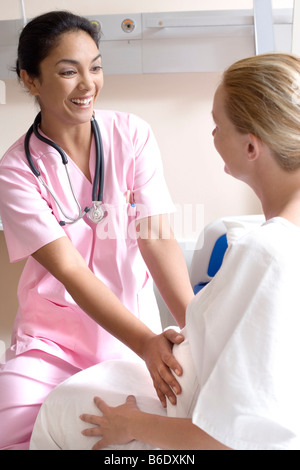 Gravidanza check-up. Ostetrico a sentire una donna pregant's addome per monitorare la posizione del feto in utero. Foto Stock