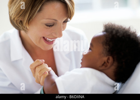 Esame pediatrico. Medico giocando con il suo 5-mese-vecchio paziente di sesso maschile durante un esame. Foto Stock