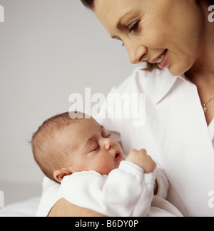 La madre e il bambino ragazza.12 settimana vecchia ragazza bambino addormentato nella sua madre armi. Foto Stock