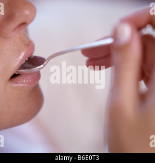 Mangiare frutta uva donna collocando un segmento di mosto di frutta su un cucchiaio nella sua bocca. Foto Stock