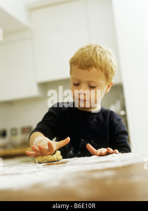 Fare biscotti. Tre anni di vecchio ragazzo cantare mentre la laminazione di una pasta biscotto. Foto Stock