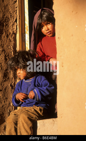 Due bambini Aymara guardando fuori attraverso una porta su Isla Taquile sul Lago Titicaca in Perù. Foto Stock