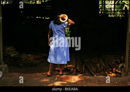 Una bambina si erge nei pressi di un negozio di macchine per la lavorazione del legno a Thrissur vicino a Cochin Kochi India Kerala Foto Stock