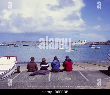 Fila di gente seduta sul lungomare, St Marys Isole Scilly Cornwall Regno Unito Foto Stock