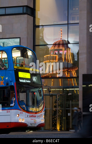 I mezzi di trasporto pubblici, finestra riflessioni; Natale, giostre, eventi e attrazioni in Princess Street, Edimburgo, Scozia, Regno Unito Foto Stock