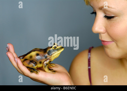 Giovane donna con una rana in mano cercando il suo perfetto principe Foto Stock