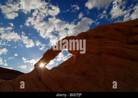 Raggi di sole e di un arco in pietra arenaria del paesaggio della Valle di Fire State Park in Nevada, Stati Uniti Foto Stock