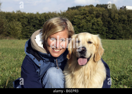 Golden Retriever (Canis lupus f. familiaris), giovane donna con il suo cane su un prato, ritratto, Germania Foto Stock