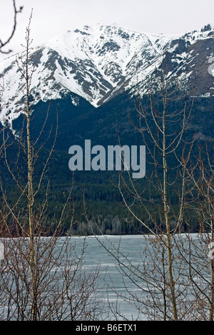 Mountain top torreggia su un lago ghiacciato in BC Canada Foto Stock