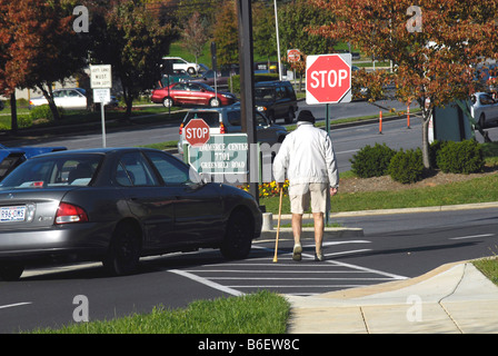 Senior Citizen passeggiate in un crosswalk mentre una unità auto intorno a lui Greenbelt Md Foto Stock