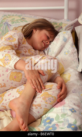 Giovane ragazza nel letto che stringe la gamba del dolore Foto Stock