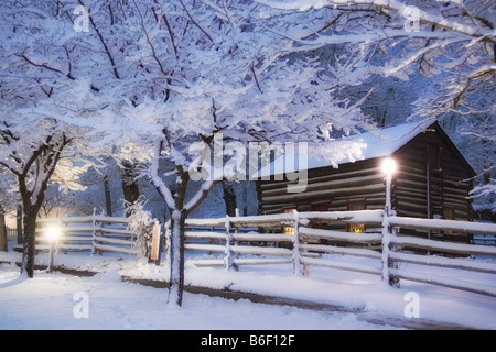 Una pittoresca vecchia cabina pioneer circondato da alberi innevati al tempo di Natale nel villaggio di pionieri del Parco Statale di Salt Lake City nello Utah Stati Uniti d'America Foto Stock