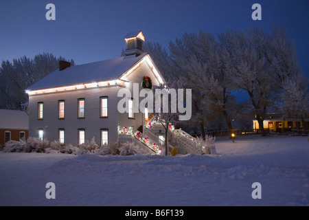 Una pittoresca vecchia chiesa pioneer circondato da alberi innevati al tempo di Natale nel villaggio di pionieri del Parco Statale di Salt Lake City nello Utah Stati Uniti d'America Foto Stock