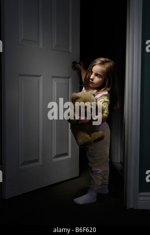 Bambina guardando fuori di una stanza a notte Foto Stock