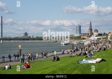 Giovani rilassante lungo le sponde del Reno di fronte la Renania settentrionale-Vestfalia il Parlamento, Duesseldorf, Germania Foto Stock