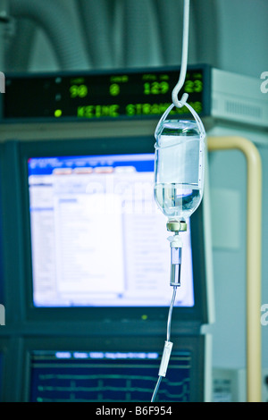 Bottiglia per infusione di fronte ad uno schermo in una sala operatoria Foto Stock