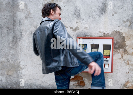 Giovane uomo calci un chewing gum distributore Foto Stock