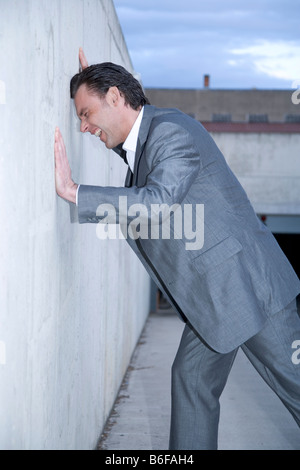 Imprenditore disperato sbattendo la testa contro il muro Foto Stock