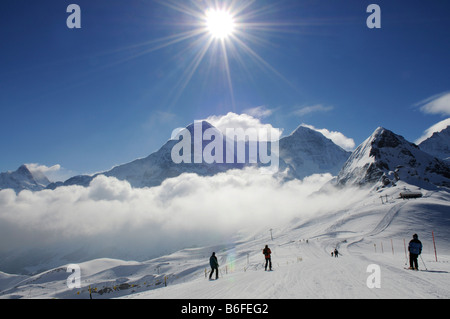 Sciatore sul Maennlichen con vista del monte Wetterhorn, Mt Eiger, Mt Moench e Mt Tschuggen, Grindelwald, Alpi Bernesi, Switzerla Foto Stock