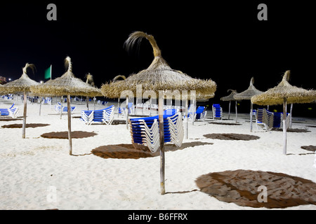 Ombrelloni e sdraio impilati sulla spiaggia di Sa Coma di notte, Maiorca, isole Baleari, Spagna, Europa Foto Stock