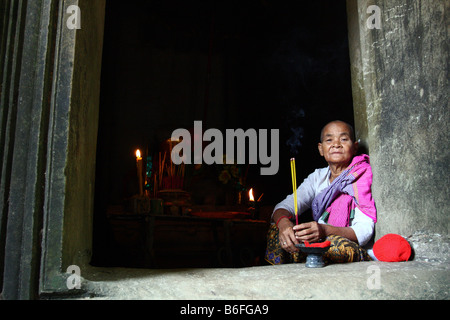 Anziani di sesso femminile monaco in bianche vesti, tenendo alcuni bastoncini di incenso al tempio Thommanon Angkor Wat Cambogia Foto Stock