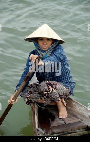 Donna che indossa un cono a forma di cappello, remare una barca, Hoi An, Vietnam, sud-est asiatico Foto Stock