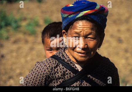 Una donna Hmong porta a suo nipote sulla sua schiena vicino a Phonsavan, Xieng Khuang Provincia, Laos Foto Stock