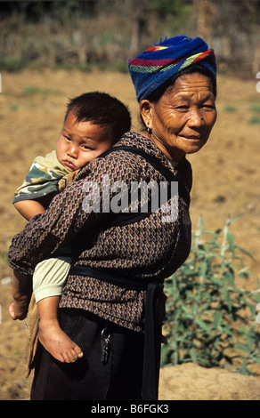 Una donna Hmong porta a suo nipote sulla sua schiena vicino a Phonsavan, Xieng Khuang Provincia, Laos Foto Stock