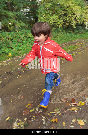 Bambino di indossare stivali di gomma a piedi attraverso pozzanghere, Niederwerth, Renania-Palatinato, Germania, Europa Foto Stock