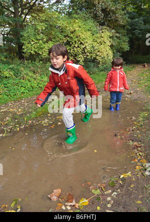 Bambini indossare stivali di gomma a piedi attraverso pozzanghere, Niederwerth, Renania-Palatinato, Germania, Europa Foto Stock