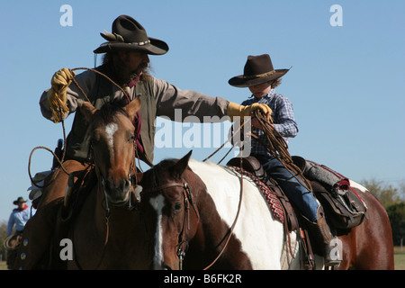 Un cowboy padre mostra il suo Figlio come corda una mucca al ranch Foto Stock