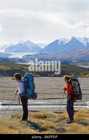 Due giovani donne, backpackers, escursionisti godendo della vista sul ghiacciaio Donjek, Big Horn Creek, St. Elias montagne, Donjek rotta Kl Foto Stock