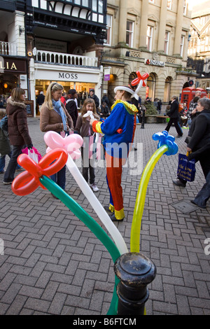 Regno Unito Chester Cheshire Eastgate Street Natale intrattenitore di strada ben l'uomo dei palloncini rendendo forma animale per bambino Foto Stock