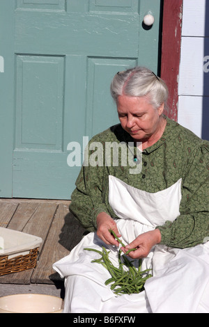 Una nonna figura fagioli a scatto sul suo portico agriturismo nel paese Foto Stock