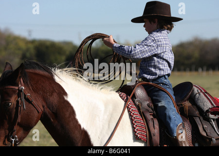 Un giovane cowboy come ottenere la corda pronto a lanciare da cavallo Foto Stock
