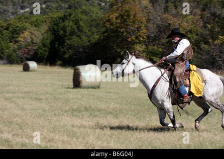 Un cowboy al galoppo a piena velocità in un texano hayfield in autunno Foto Stock