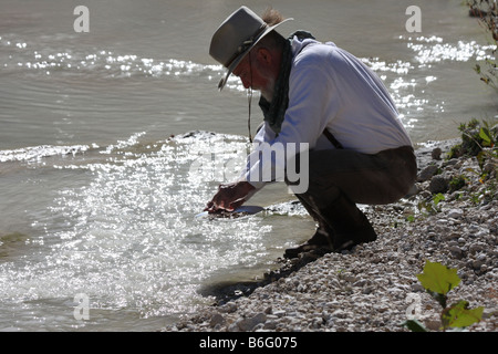 Una rivendicazione digger il panning per oro in un flusso in Texas la luce è splendenti fino dall'acqua in padella Foto Stock