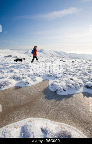 Una donna che cammina sulla Caudale Moor guardando verso il Kentmere Fells sopra Ambleside nel distretto del lago REGNO UNITO Foto Stock