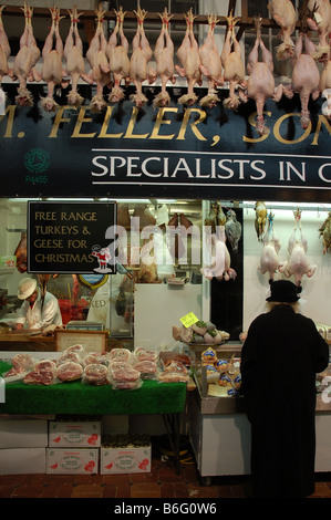 Old Lady il controllo della carne al di fuori M Feller figlio e figlia Organico negozio di macellaio prima di Natale nel mercato coperto, Oxford Foto Stock